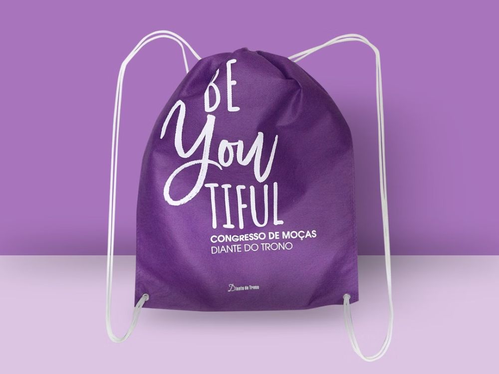 Sacochila roxa personalizada com mensagem motivacional usada como um dos brindes para motivar equipe em eventos.