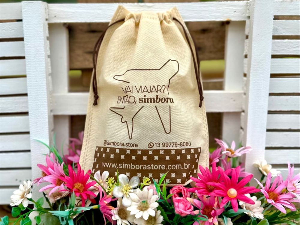 A sacola da "simbora.store" com a frase "Vai viajar? Então, simbora" e a foto do cachorro, envolta por flores, sugere que a marca tem um propósito que vai além da venda, possivelmente relacionado a viagens e bem-estar animal. Isso demonstra um exemplo de o que é marketing socioambiental que busca criar uma conexão emocional com o público através de valores compartilhados.