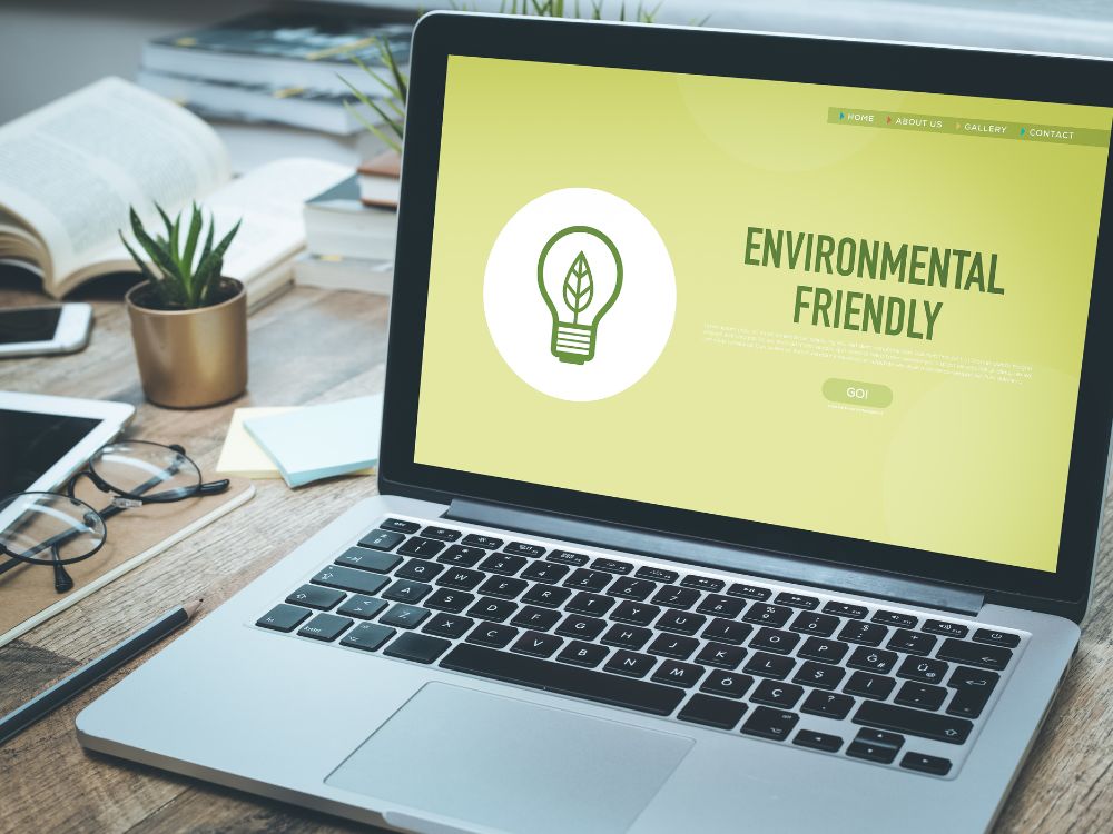 A foto do laptop com a tela "Environmental Friendly" mostra como as empresas comunicam seu compromisso ambiental através de plataformas digitais, como sites e campanhas online. Um exemplo do que é marketing empresarial focado em sustentabilidade.