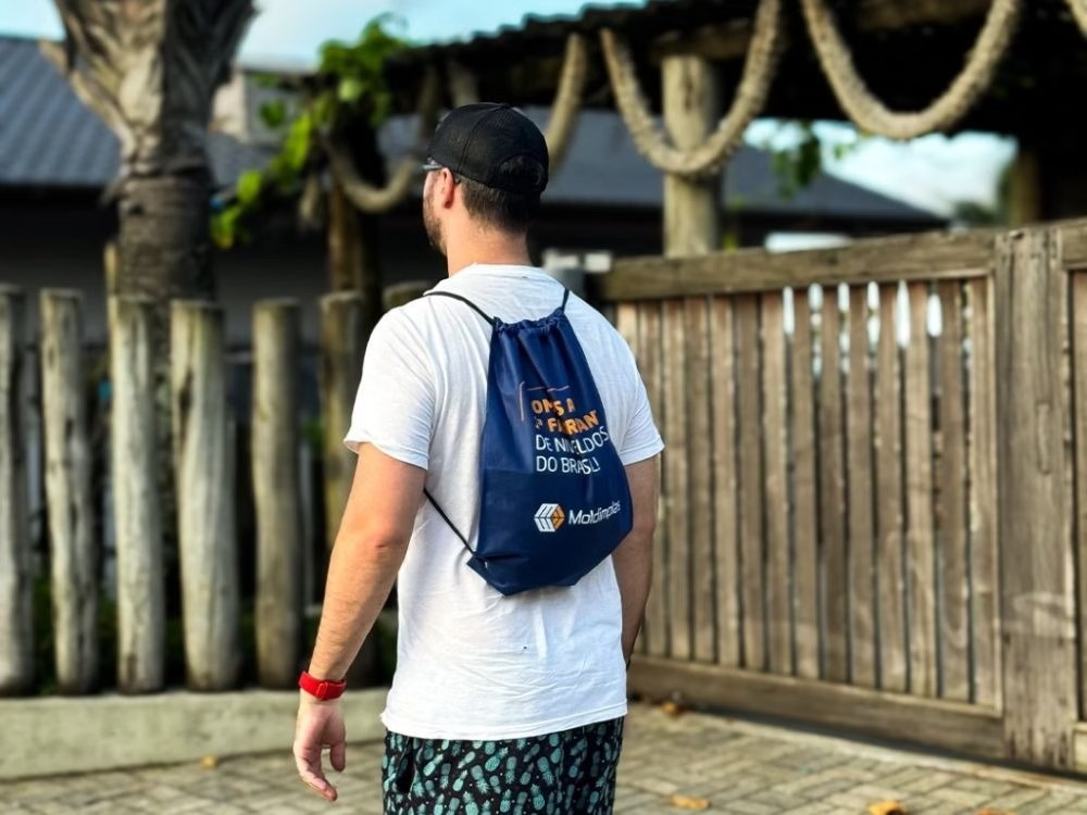 Sacochila de TNT azul em uso no dia a dia, modelo leve e resistente que reforça o uso consciente de produtos sustentáveis.