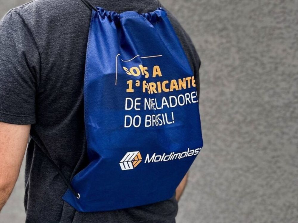 Homem usando mochila personalizada com logotipo Brinde corporativo criativo entre as 6 ideias para presentear clientes e divulgar sua marca com utilidade.