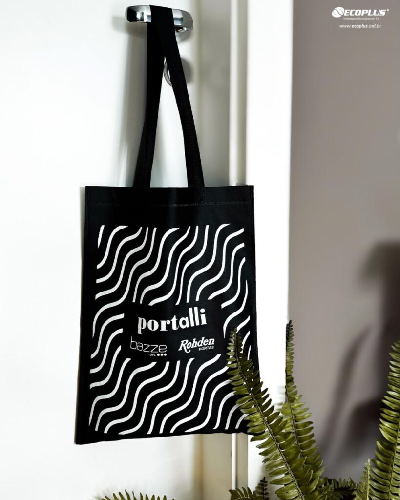 A sacola TNT com alça da cor preta com estampa branca. Uma excelente embalagem reutilizável para lojas.