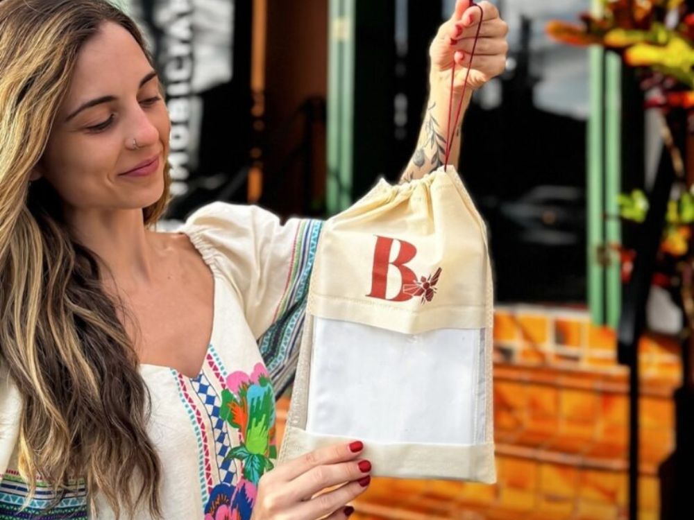Mulher segurando sacola de tecido personalizada. Embalagens ecológicas personalizadas são ótimas entre as 6 ideias para presentear clientes com elegância.