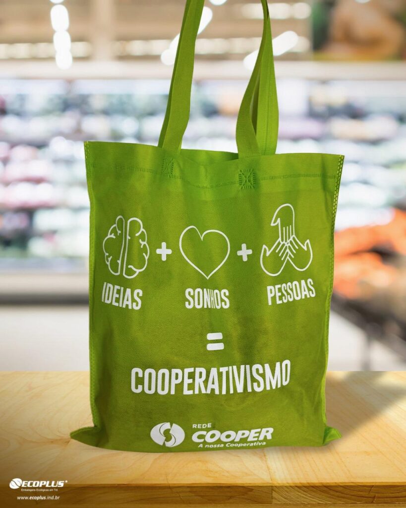 Sacola verde personalizada da Rede Cooper com a frase “Ideias + Sonhos + Pessoas = Cooperativismo”, representando uma das 6 ideias para presentear clientes de forma sustentável.