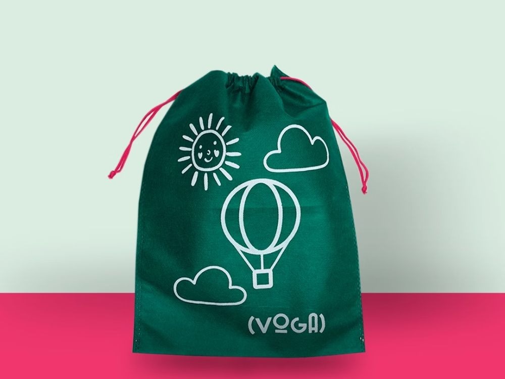 Saco de tecido verde com estampa de balão e sol da marca Voga, exemplo de Brindes úteis e criativos para eventos e campanhas.