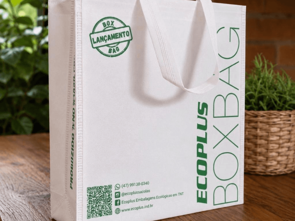 Embalagem Box Bag de TNT com alças reforçadas e impressão personalizada, desenvolvida para oferecer mais resistência e reutilização.