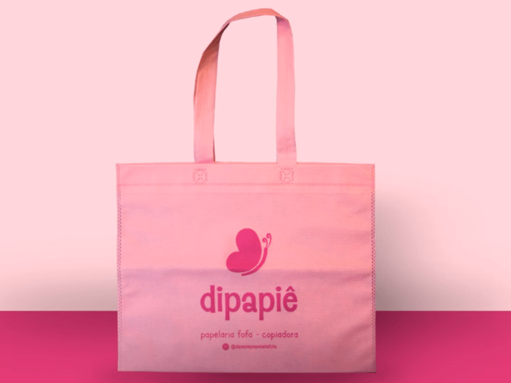 Ecobag rosa da papelaria Dipapiê com alças longas e logotipo em tom de rosa mais escuro na parte central.