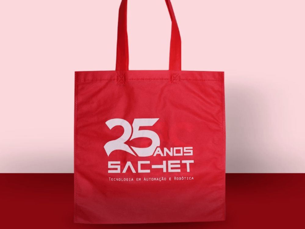 Ecobag vermelha personalizada da SAC-HET com alças compridas e impressão branca comemorativa de 25 anos na parte frontal.